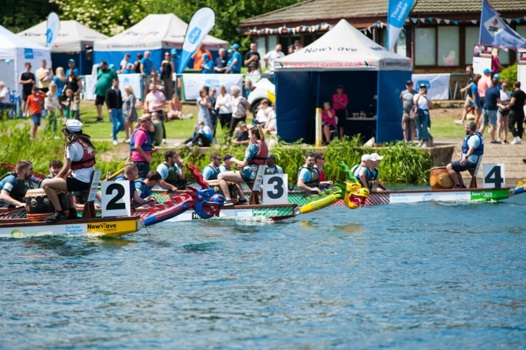 Teams paddling together during a corporate dragon boat racing event