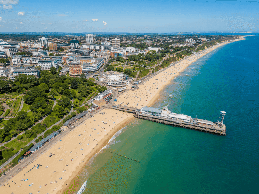 Drone view of Bournemouth on a sunny day, overlooking Bournemouth Pier, the sandy beach, seafront gardens and coastline.