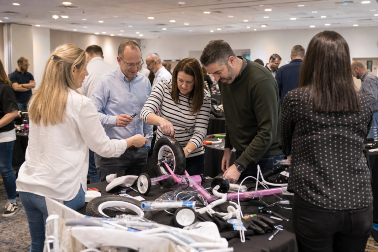 A UK corporate team assembling charity bikes together at an indoor event