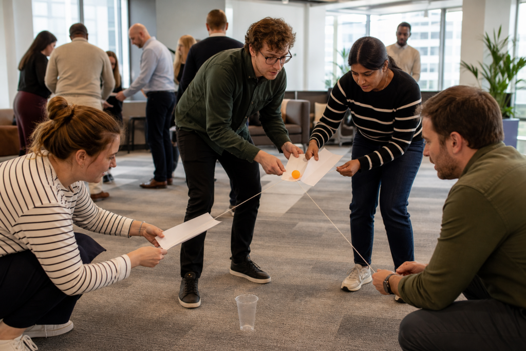 Colleagues playing taskmaster-style office games in a bright office breakout space