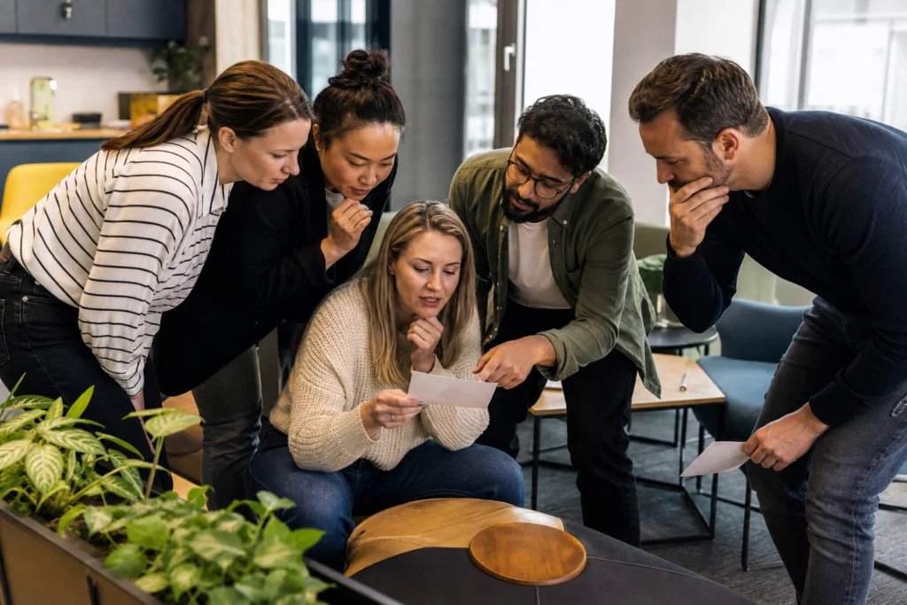 Colleagues working together on an indoor office treasure hunt clue