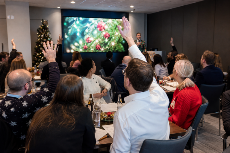 UK corporate team taking part in a festive Christmas quiz with a quizmaster in a conference room
