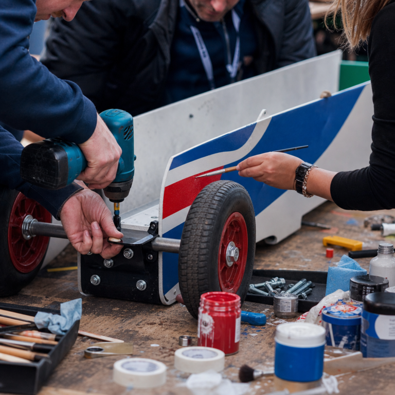 Close-up of team members building and decorating their Soap Box Derby cart with tools and craft materials
