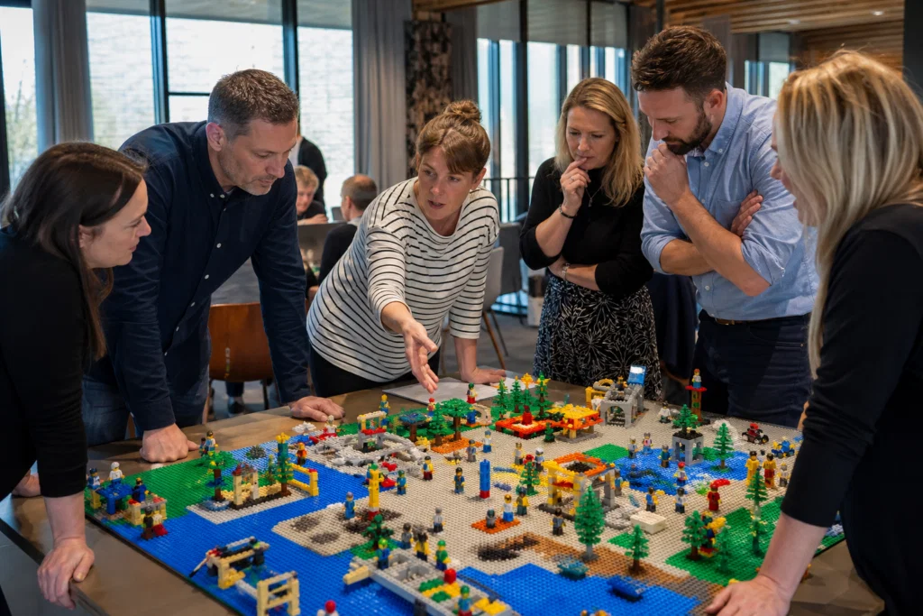 Team discussing a shared Lego model during a corporate away day